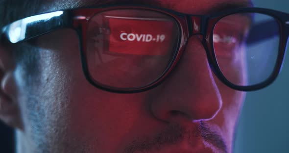 Reflection in Eyeglasses Coronavirus Warning Man Using Laptop Reading News About Covid 19 at Night