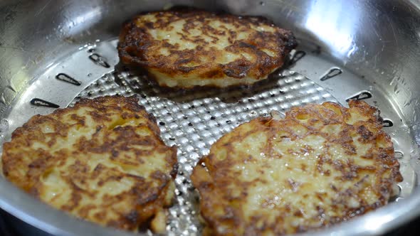 The cook fries zucchini pancakes in a pan