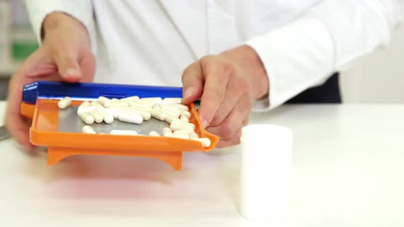 Pharmacist putting pill in container at pharmacy