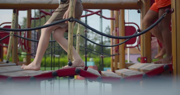 Cropped Shot of Barefoot Children Walk Across Rope Bridge on Playground