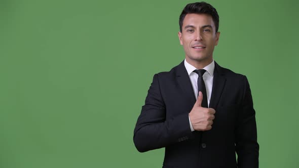 Young Handsome Hispanic Businessman Against Green Background