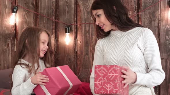 Mother and a Cute Little Girl Holding Xmas Presents and Trying To Guess What's Inside