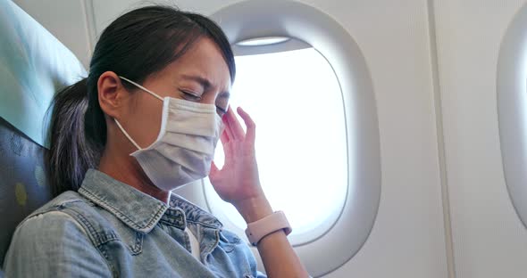 Woman feeling unwell and wearing face mask on plane