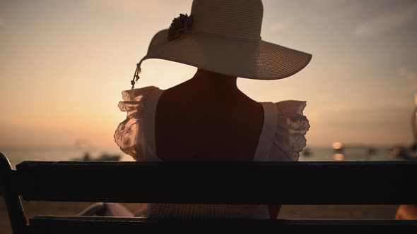 Back of Caucasian Woman in Hat Seating Face to Ocean