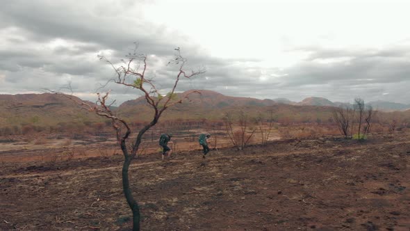 Aerial tracking, Hikers in burnt landscape with distant mountains