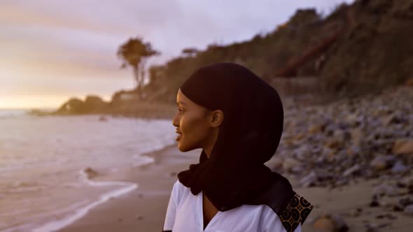 Somali-American woman walking on the beach at sunset