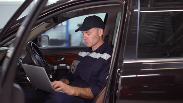 Mechanic Working on Laptop in Auto Repair Service Inside the Car Close Up