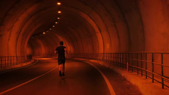 Man jogging alone in empty car tunnel.