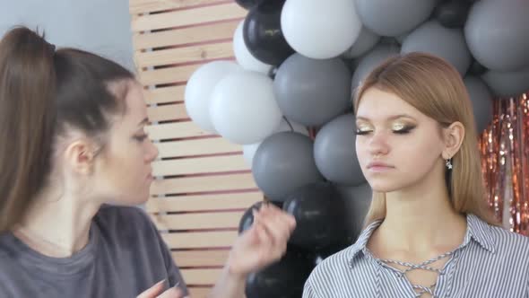 A Beautiful Young Girl Makeup Artist Makes Makeup for a Model Who Looks at Herself in the Mirror