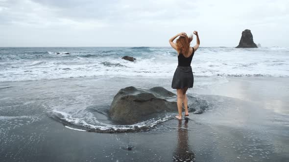 Woman in Dress Standing on a Big Rock on the Shore of the Black Volcanic Black Sand Beach Benijo in