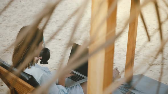 Background Shot of Focused Successful Female Freelance Worker with Drink Using Laptop Mobile Office