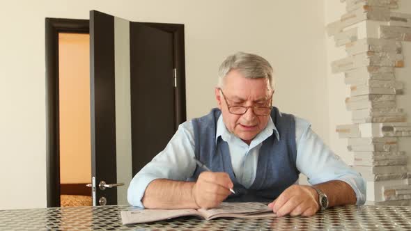 Man Unravels Crossword Puzzles, He Has Poor Eyesight and He Is Wearing Glasses