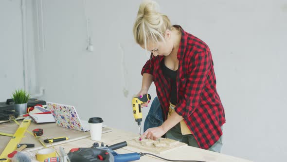 Female Drilling Wooden Plank on Workbench