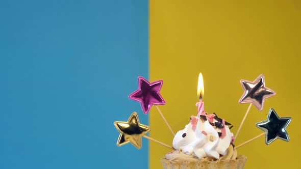 Birthday Cupcake with Candles and Birthday Decorations on a Blue and Yellow Background