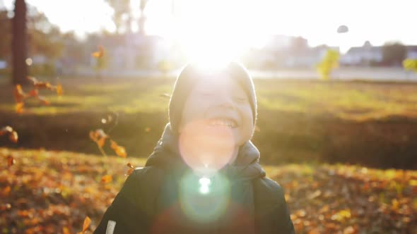 Boy Throws a Pile of Leaves Overhead and Watches Them Fall