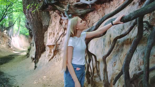 Young Blonde Woman Looking on Exposed Tree Roots in Natural Loess Ravine