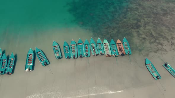 Aerial along the beach with coral bay group of long tail boats Thailand Asia