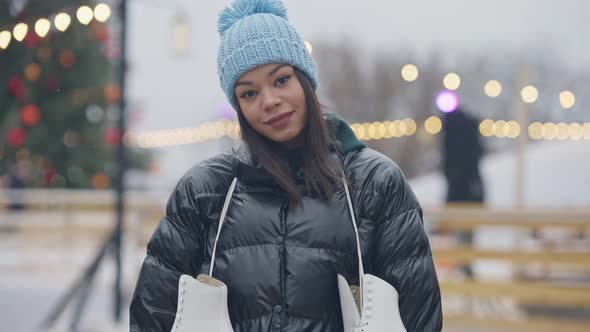 Camera Approaches to Cheerful Beautiful African American Woman Standing at Ice Rink on Misty Winter
