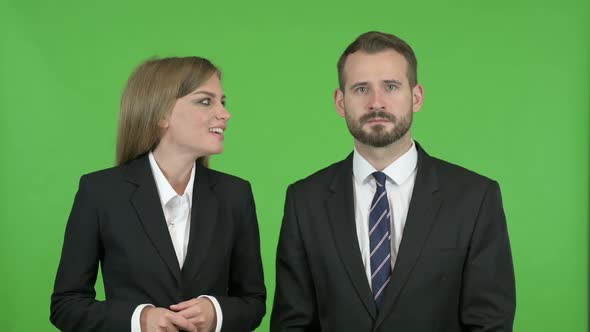 Male Professional Giving Dollar to Female Professional Against Chroma Key