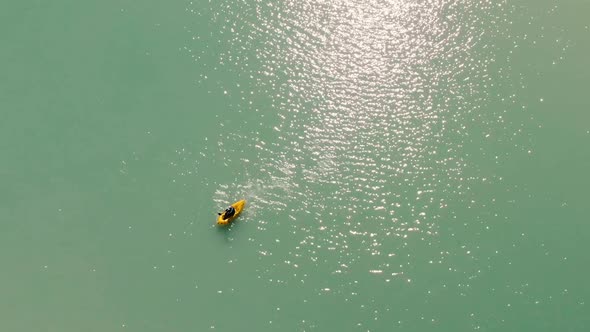 Man is Paddling on Yellow Boat in the Mountain Lake