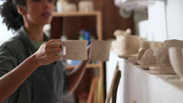 Woman potter puts cups of clay