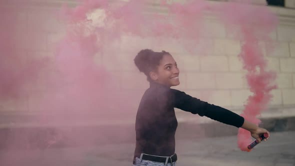 Beautiful Afro American Woman with Pink Smoke Bomb or Grenade on Bright Bricked Wall Background