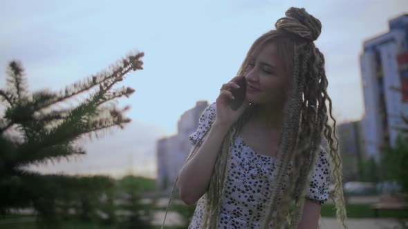 Young and Beautiful Girl Talking on a Smartphone in the Street