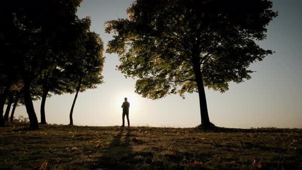 Bright Orange Sunset Sky Silhouettes of a Man and Takes a Picture on the Phone During Amazing Sunset