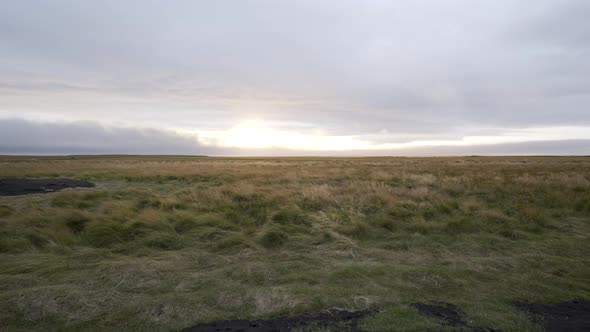 Icelandic fast moving clouds in a Lush green field with sun peeking through.