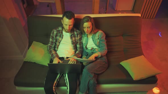 A Young Man and Woman are Using Laptop Together Looking at Screen Shopping or Chatting Online Using