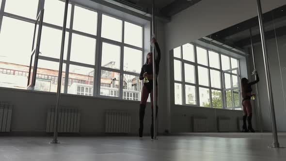 Flexible Woman Dancing on Pole in Studio