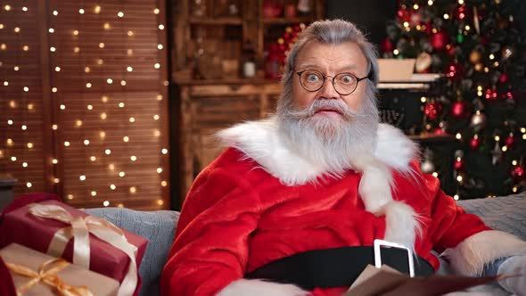 Portrait of Shocked Man in Santa Claus Costume Talking Reading Wishlist