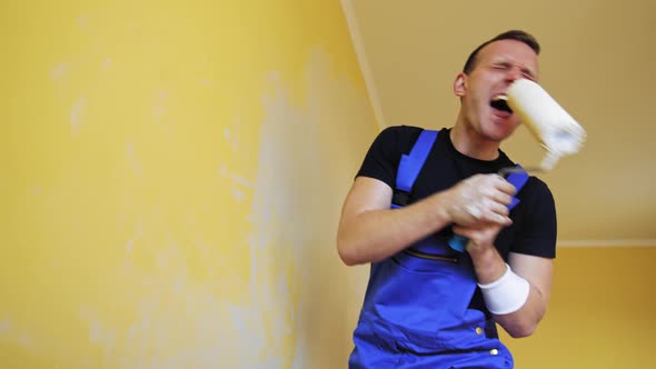 Cheerful man with rollers for painting the walls singing