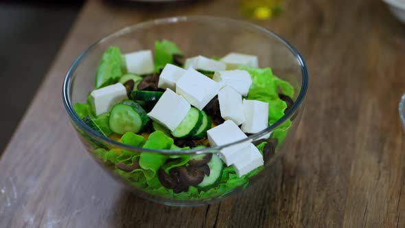 ingredients fall into a plate with green lettuce leaves. Greek salad. cheese Bulgarian pepper olives