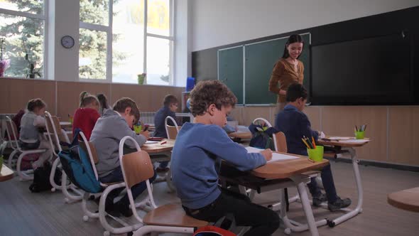 Woman Teacher Interested in Drawing of Schoolboy