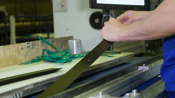 A Worker at the Factory Inserts Metal Components and Products