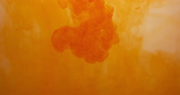 Orange Color Paint Ink Drops in Water at White Background. Inky Cloud Flowing Underwater. Abstract