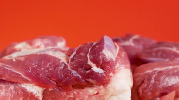 Close-up of pieces of raw pork meat rotate on a bright red background. Fatty red pork meat. Cooking 