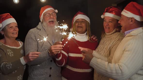 Happy seniors family celebrating Christmas holidays with sparklers fireworks at night party