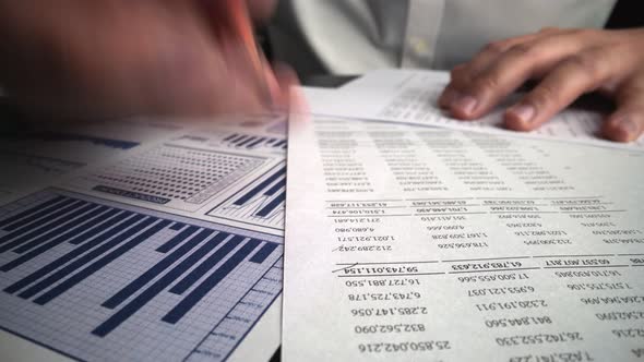 Accountant Analyzing Business Marketing Data on Paper Dashboard at Office Table