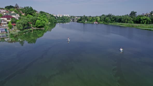 Group of Girls on the Water Simultaneously Rowing the Oars on the SAP Board