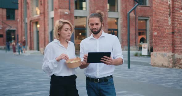 Bearded Smiling Man Shows Something on a Tablet to a Woman.