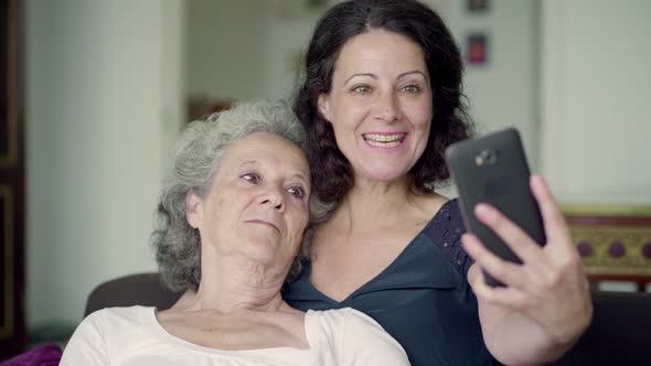 Mother Lying on Daughters Shoulder, Having Video Chat on Phone