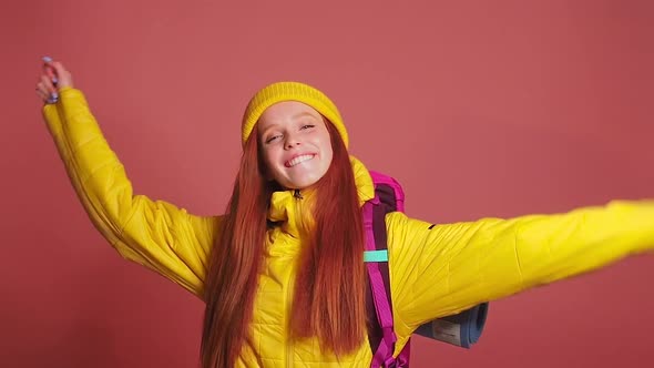 Redhaired Ginger Woman in Pink Studio Background Wearing Yellow Windbreaker Jacket with Hat and