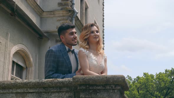 A Young Couple in Love with Two People Standing on a Stone Balcony and Looking Into Each Other's