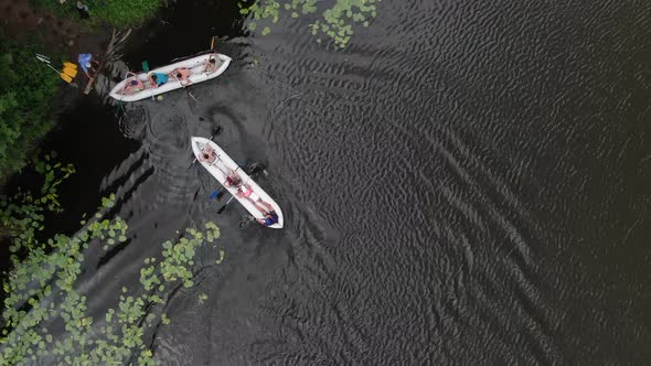 Aerial Birds-Eye View of Two Canoes Filled With People in a River Docking on Shore