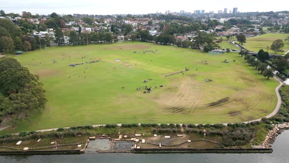 Aerial view of park or playground green field full of school kids and teachers doing activities at r