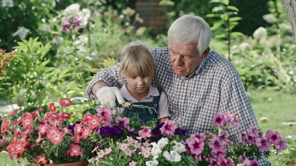 Elderly Man Teaching Granddaughter Gardening