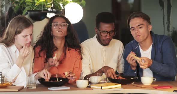 Group of Young Friends Eating Delicious Food in Cafe While Spending Time Together. Happy Coworkers