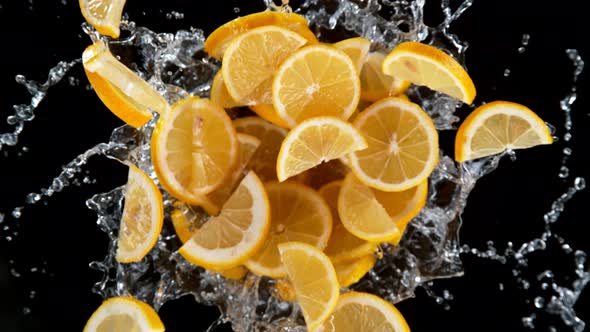 Super Slow Motion Shot of Rotating Exploded Lemon Slices with Splashing Water on Black at 1000Fps